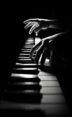 two hands are playing the piano in black and white