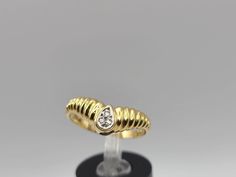 a yellow gold and diamond ring on a black stand