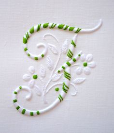 an embroidered monogram with green and white accents on a piece of cloth that has been stitched together