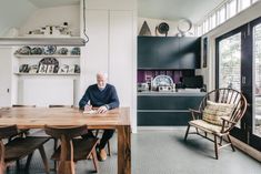 a man sitting at a wooden table in a kitchen next to a dining room set