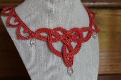 a mannequin with a red crochet necklace on it's neck