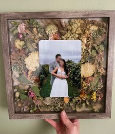 a person holding up a photo frame with flowers on it