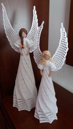 two white crocheted angel figurines on a table