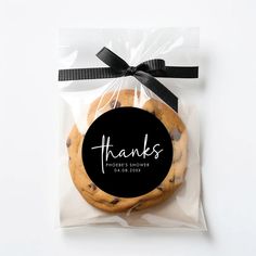 a chocolate chip cookie wrapped in cellophane with a black ribbon and thank you tag