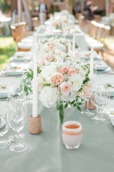 a long table is set with white and pink flowers, candles, and wine glasses