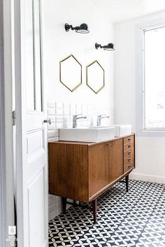 a bathroom with black and white tile flooring and two wooden vanity sinks in the corner