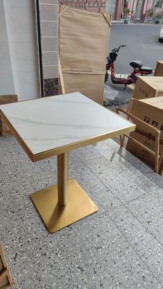 a white table sitting on top of a sidewalk next to cardboard boxes and other items