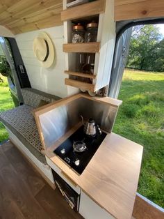 a kitchen area with a stove, sink and shelves on the side of the wall