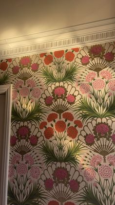 the wall paper has flowers on it and is pink, green, red and white