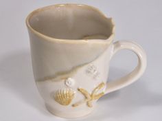 a coffee cup with seashells and starfish painted on it's side