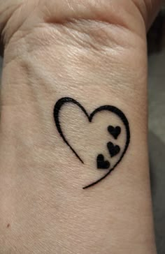 a small tattoo on the wrist of a person with a heart and three little hearts