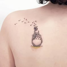 the back of a woman's shoulder with a cat and dandelion tattoo