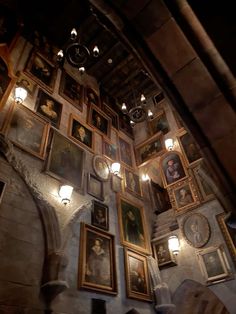 a room filled with lots of framed pictures and lights on the wall next to it