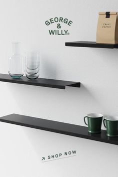 two black shelves with coffee cups and glasses on them next to a paper bag that says george & willly