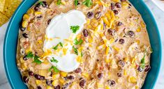 a blue bowl filled with corn and black bean dip surrounded by tortilla chips