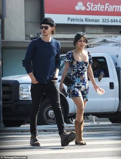 a man and woman walking across a street