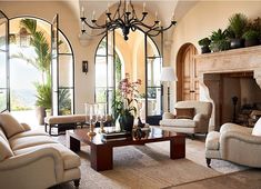 a living room filled with furniture and a fire place in front of a fireplace covered in potted plants