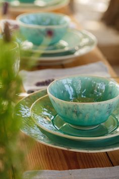 a table set with green dishes and place settings