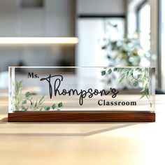 a glass sign that says, ms thompson's classroom on it sitting on a table