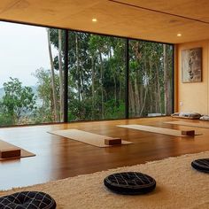 there are many mats on the floor in front of large windows with trees out side