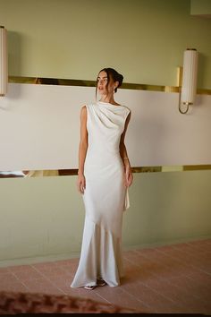 a woman in a white dress standing next to a wall with two lights on it