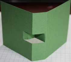 an open green box sitting on top of a cutting board with a hole in the middle