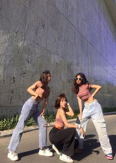 three young women are posing in front of a wall