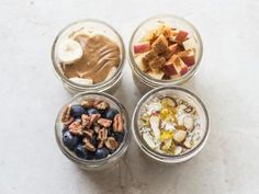 four small glass jars filled with different types of food and nuts on a white surface