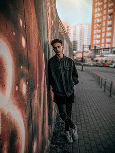 a man standing next to a wall with graffiti on it