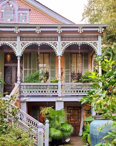 an old house with lots of plants in the front yard and stairs leading up to it