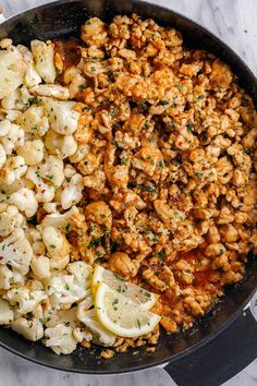 cauliflower and lemon in a skillet on a marble surface