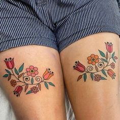 two women with matching tattoos on their legs, one has flowers and the other has leaves