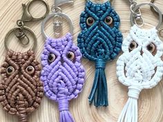 four different key chains with eyes and tassels attached to each other on a wooden surface