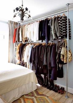 a bedroom with a bed, chandelier and clothes on the rack in it