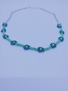 This daisy chain necklace reminds one of the gentle daisies and flowers that grow during springtime. The flowers are made with bright blue seed beads (with one yellow bead in the middle-how cute) paired with shining green seed beads to connect the flowers. The flowers are so small and dainty, you just can't help but smile. This piece may not be "in-your-face" but it is sure to make a subtle statement. (That statement is that you love flowers.) The entire length of the necklace is 16 inches to 18 inches with the extender chain. The flowers make up the middle eight inches and are flanked on both sides by a shiny, silver chain. Daisy Chain Necklace, Beaded Flower Necklace, Your Face, Flowers Jewelry, In Your Face, Daisy Chain, Necklace Beaded, Wedding Jewellery Necklace, Necklace Blue