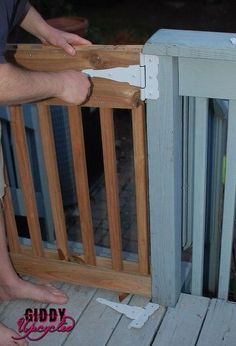 a man standing on top of a wooden deck next to a fence and holding onto the railing