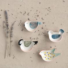 three ceramic birds sitting on top of a table next to dried flowers and lavender sticks