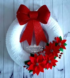 a paper plate wreath decorated with poinsettis and a red bow on top