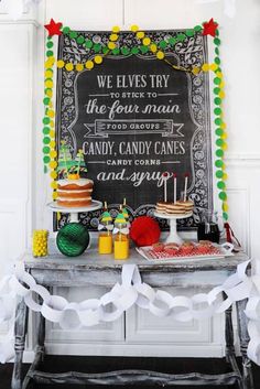 a chalkboard sign is on the wall behind a table with candy and candies