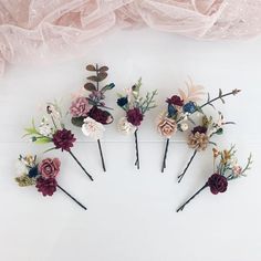 six flower hair pins in various colors and sizes on a white surface with pink tulle