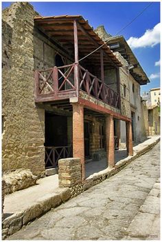 an old brick building with a balcony and balconies on the second floor, in front of a cobblestone street