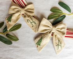 three bows with embroidered letters and trees on them