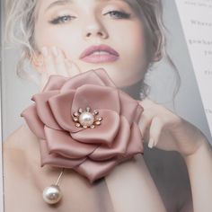 a woman wearing a pink flower and pearl brooch