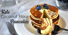 a stack of pancakes topped with blueberries and butter on top of a white plate