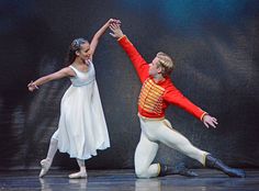 two dancers in red and white outfits, one holding the other's hand