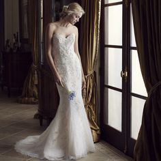 a woman in a wedding dress standing by a window