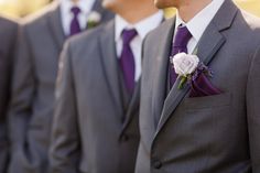 a group of men in suits standing next to each other wearing purple ties and flower boutions