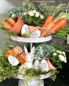 three tiered tray with carrots, flowers and bunny figurines on it