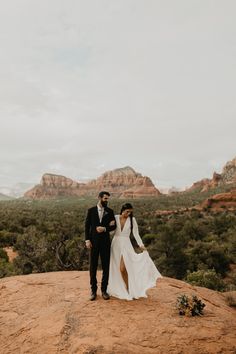 a bride and groom standing on top of a mountain