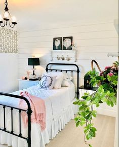 a bedroom with white walls and black iron bed frame, flowers on the nightstands